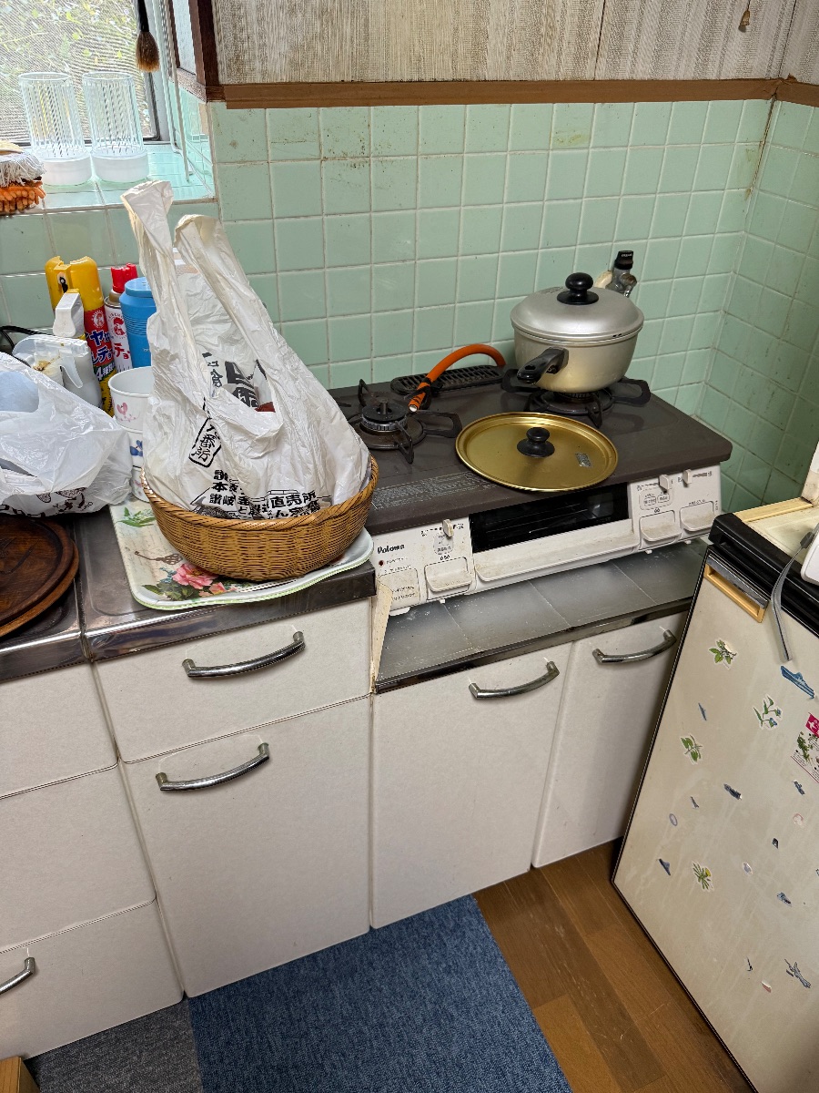 井原市 台所の不用品回収前の流し台とコンロまわりに置かれた鍋や日用品の様子